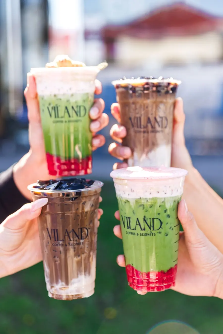 Four ViLand drinks, including matcha and grass-jelly lattes, held outdoors.