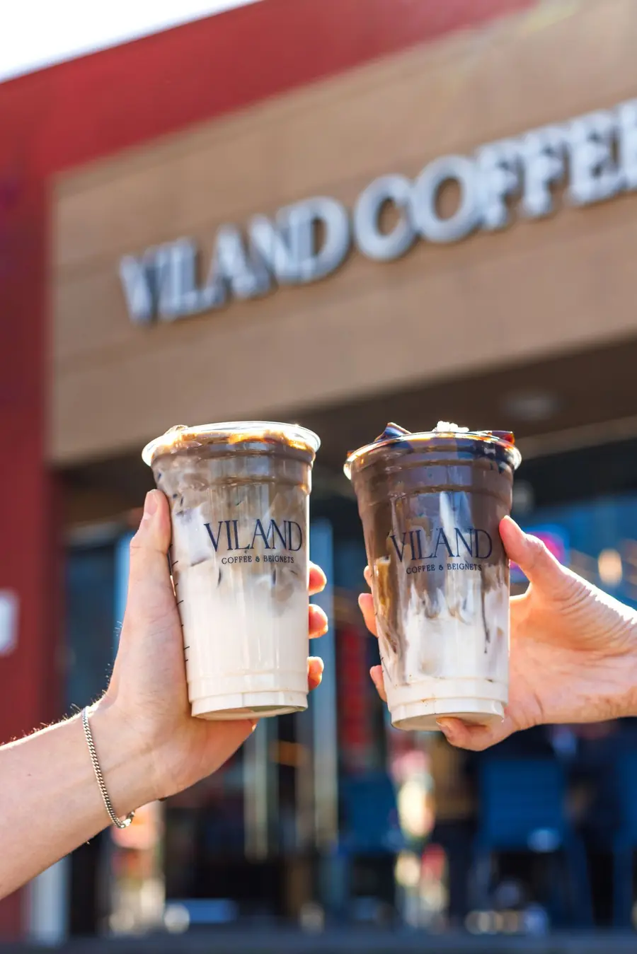 Two ViLand drinks held in front of the storefront.